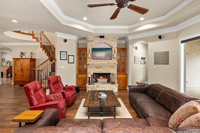 living room with arched walkways, a ceiling fan, dark wood-style flooring, and a raised ceiling