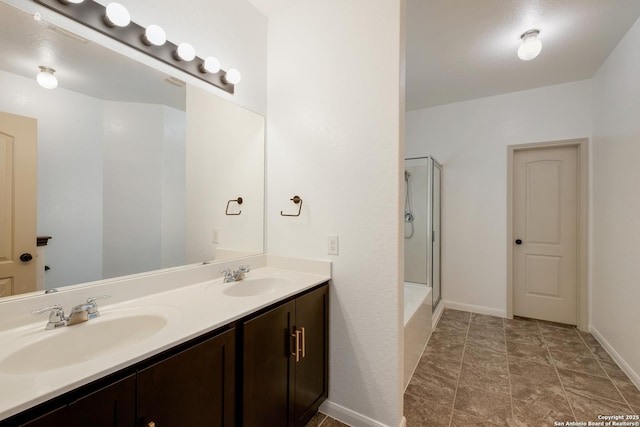 bathroom featuring double vanity, a sink, a shower with door, and baseboards