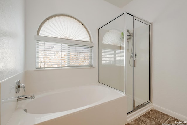 bathroom featuring a stall shower, a bath, and tile patterned flooring