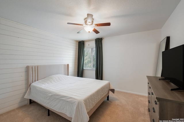 bedroom with baseboards, ceiling fan, wooden walls, and light colored carpet