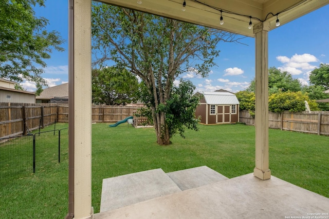 view of yard featuring a patio area, an outbuilding, a fenced backyard, a storage shed, and a playground