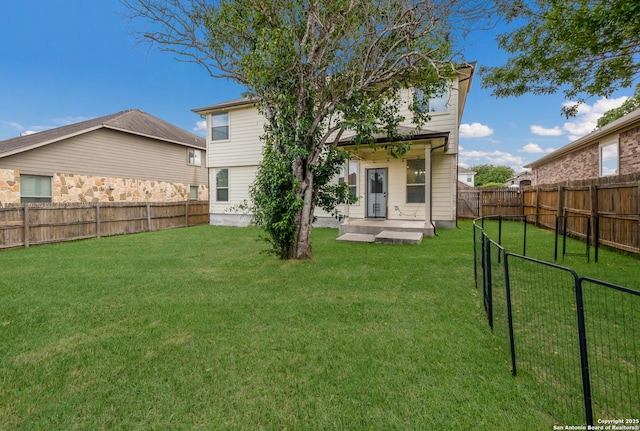 rear view of property featuring a yard and a fenced backyard