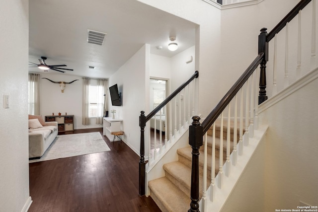 stairway featuring a ceiling fan, visible vents, wood finished floors, and baseboards