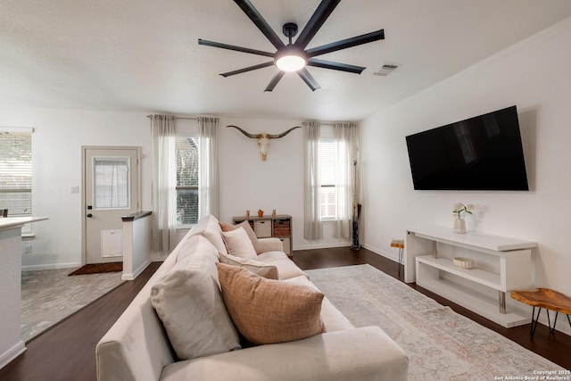 living room with ceiling fan, visible vents, dark wood-style floors, and baseboards