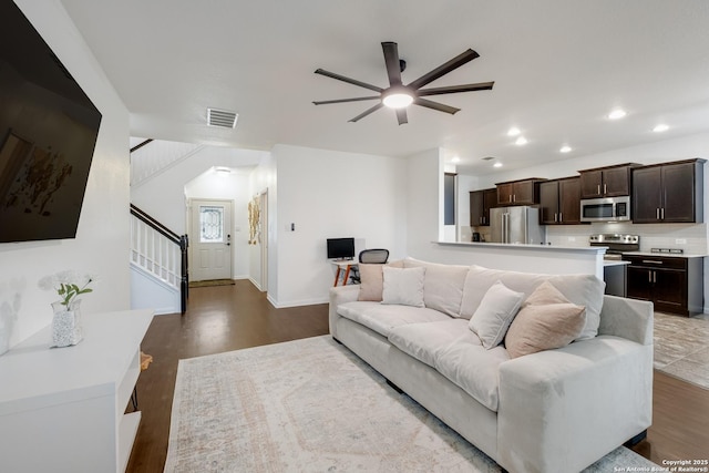 living room featuring wood finished floors, visible vents, ceiling fan, and stairs