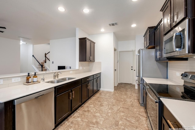 kitchen with backsplash, appliances with stainless steel finishes, light countertops, and a sink