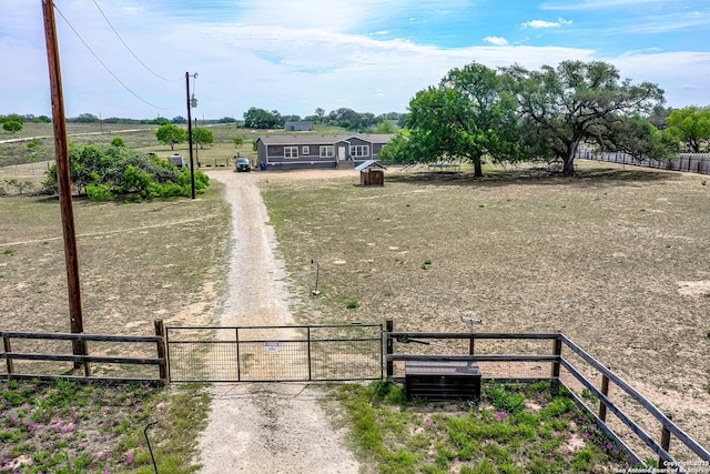 view of yard with fence, a gate, and dirt driveway