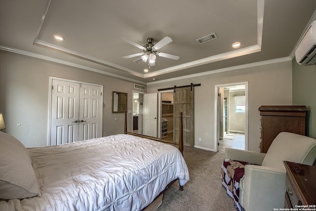 carpeted bedroom featuring visible vents, a wall unit AC, a barn door, and a tray ceiling