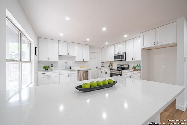 kitchen with a sink, white cabinetry, stainless steel appliances, and decorative backsplash