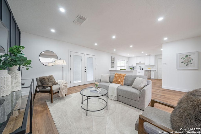 living area with visible vents, light wood-type flooring, and recessed lighting