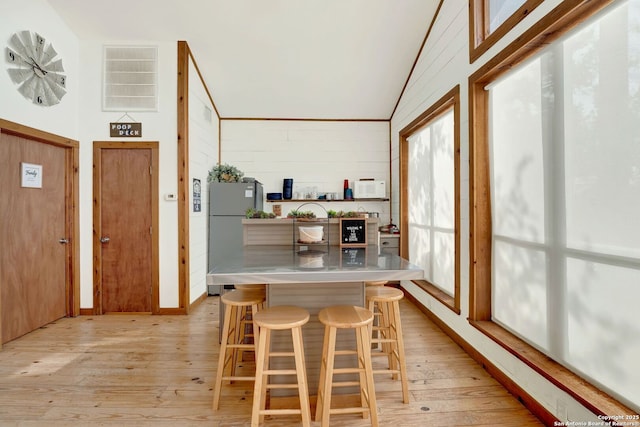 interior space with light wood finished floors, visible vents, and high vaulted ceiling