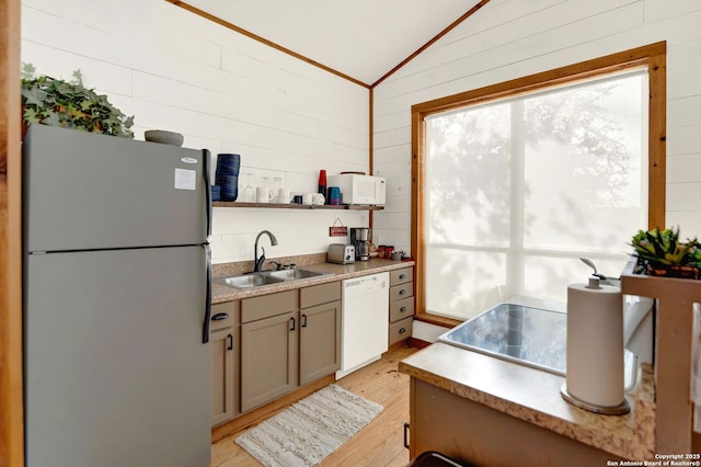 kitchen featuring white appliances, a sink, light wood-type flooring, wooden walls, and lofted ceiling