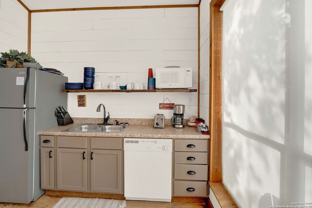 bar with white appliances, light wood finished floors, and a sink