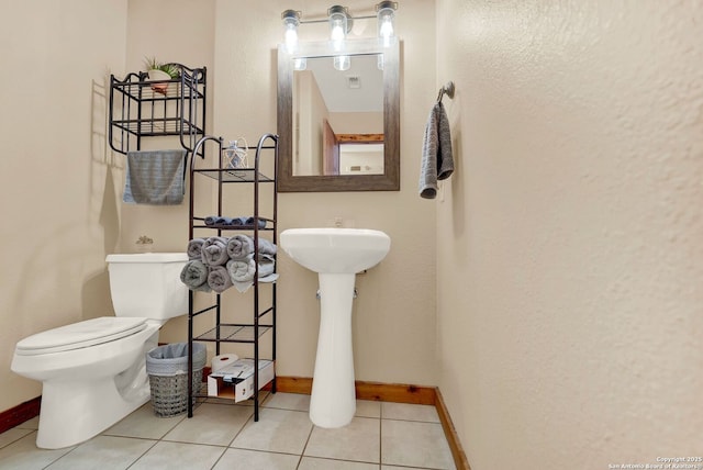 bathroom with toilet, tile patterned floors, and baseboards