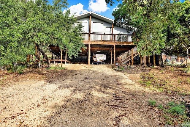 view of front of property featuring a carport, stairway, a wooden deck, and dirt driveway