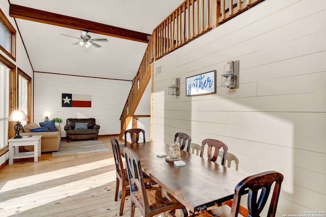 dining area with visible vents, wood walls, lofted ceiling with beams, and light wood-style floors