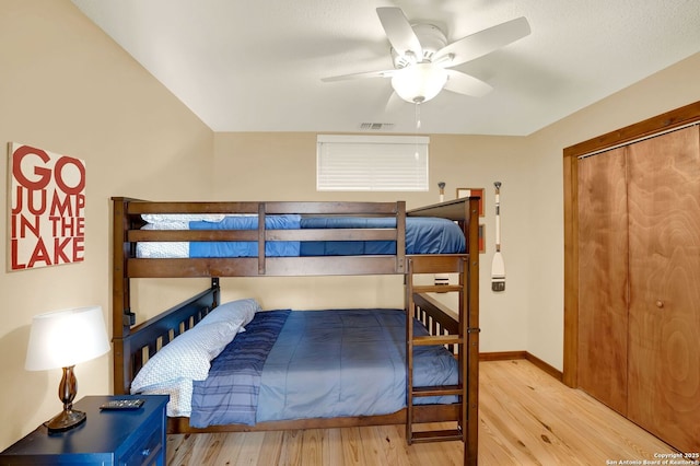 bedroom with wood finished floors, visible vents, a ceiling fan, and baseboards