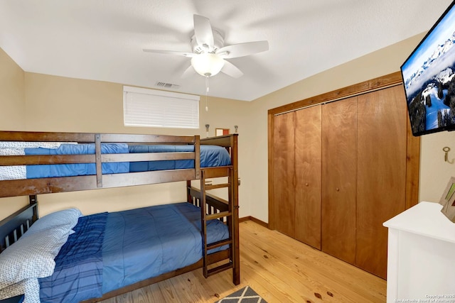 bedroom with visible vents, light wood-type flooring, a ceiling fan, and a closet