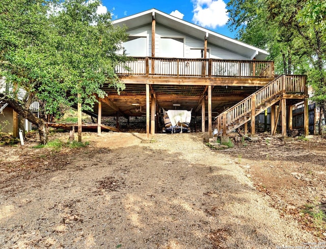 rear view of house with a deck, a carport, driveway, and stairs