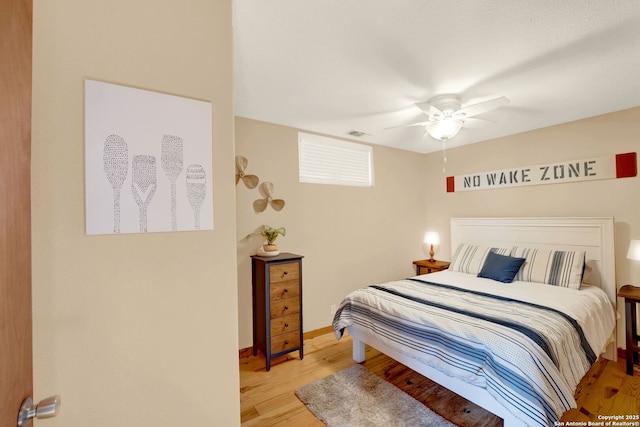 bedroom featuring visible vents, ceiling fan, light wood-style flooring, and baseboards