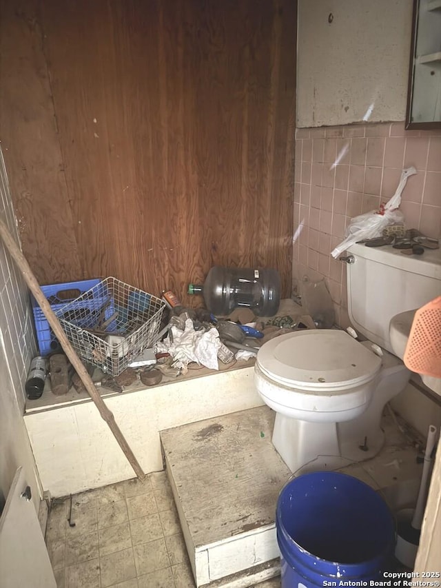 bathroom featuring tile patterned floors, toilet, and tile walls