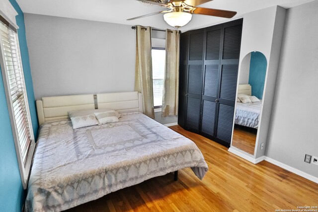 bedroom with baseboards, wood finished floors, a ceiling fan, and a closet