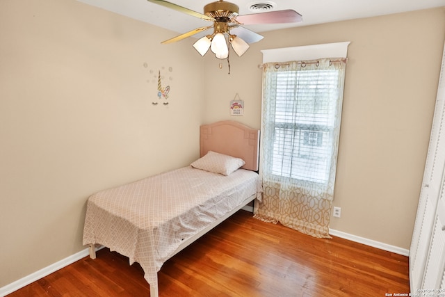 bedroom with wood finished floors, ceiling fan, visible vents, and baseboards