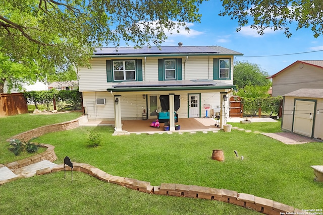 back of property featuring a patio, a yard, a fenced backyard, roof mounted solar panels, and a storage unit