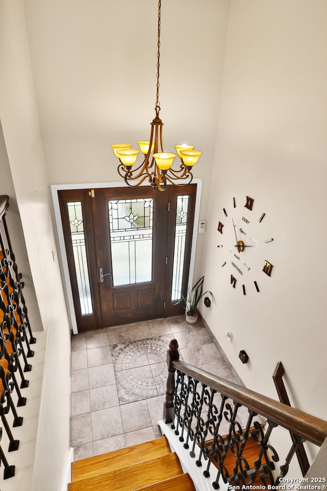 entrance foyer featuring light tile patterned floors, a notable chandelier, stairs, and a high ceiling