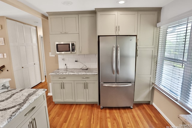 kitchen featuring light wood-style floors, stainless steel appliances, backsplash, and baseboards