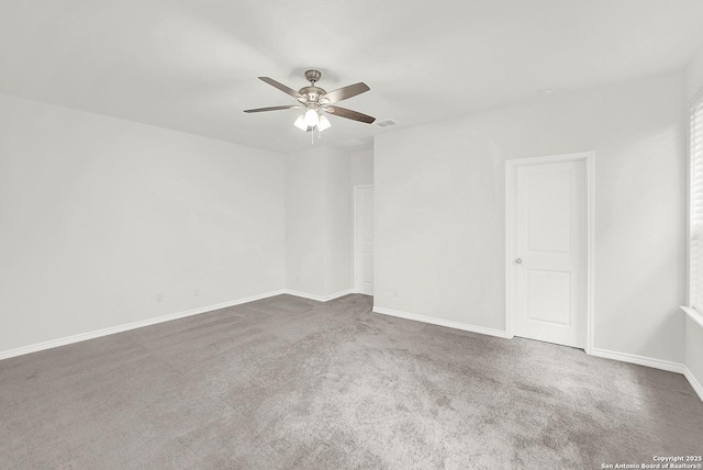 carpeted empty room with ceiling fan, visible vents, and baseboards