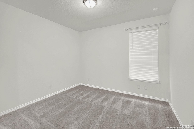 unfurnished room featuring a textured ceiling, carpet, and baseboards