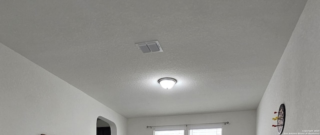 details featuring a textured ceiling, visible vents, and arched walkways