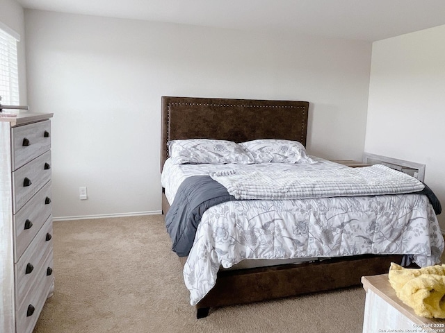 bedroom with light colored carpet and baseboards