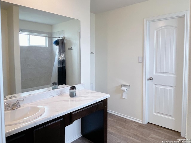 bathroom featuring baseboards, wood finished floors, a shower with shower curtain, and vanity