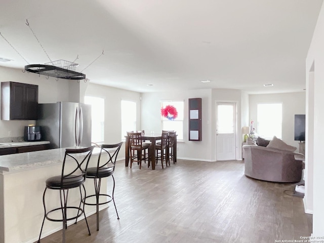 kitchen with a kitchen bar, a healthy amount of sunlight, freestanding refrigerator, and light wood-style floors