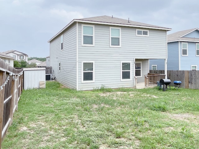 back of house featuring central AC, a fenced backyard, and a lawn