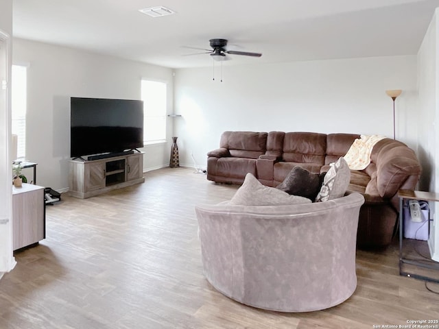 living area featuring visible vents, ceiling fan, light wood-style flooring, and baseboards