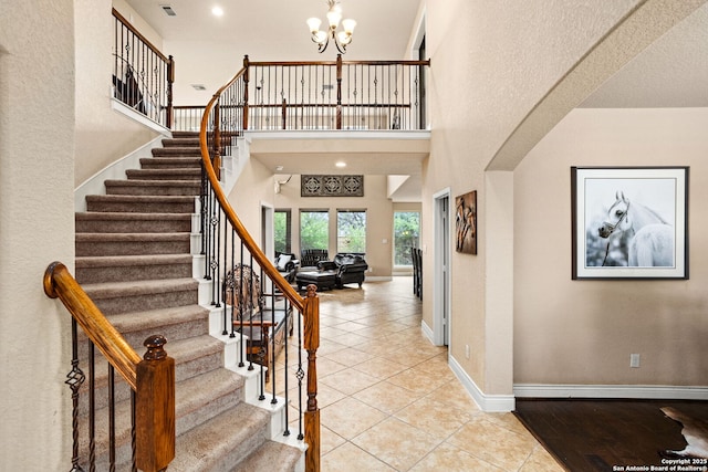 tiled entrance foyer featuring baseboards, stairway, a chandelier, and a towering ceiling