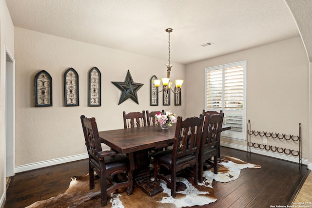 dining space featuring visible vents, hardwood / wood-style floors, a notable chandelier, and baseboards