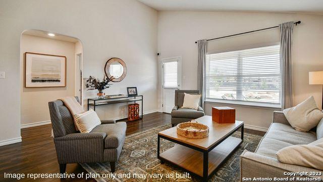 living area with wood finished floors, vaulted ceiling, and baseboards