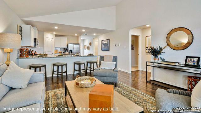 living room featuring recessed lighting, arched walkways, dark wood-style flooring, baseboards, and high vaulted ceiling