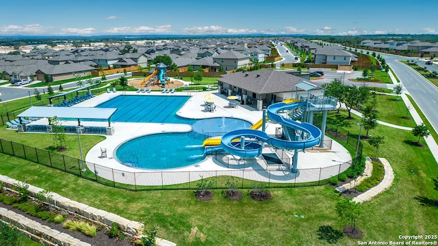 pool with fence, playground community, a water slide, and a residential view