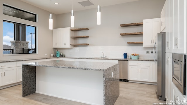 kitchen featuring light wood-style floors, stainless steel appliances, open shelves, and white cabinetry