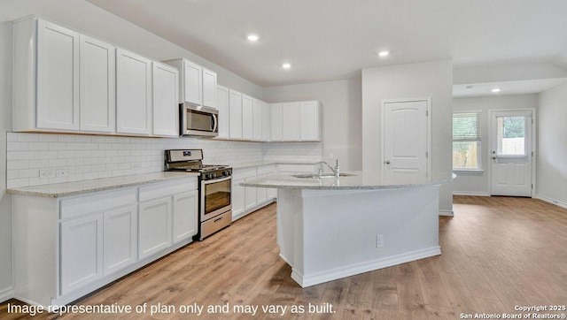 kitchen with tasteful backsplash, appliances with stainless steel finishes, light wood-style flooring, and a sink