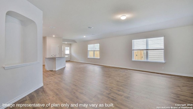 unfurnished living room featuring recessed lighting, wood finished floors, and baseboards