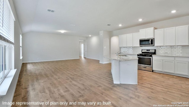 kitchen with a sink, light wood-style floors, visible vents, stainless steel appliances, and backsplash