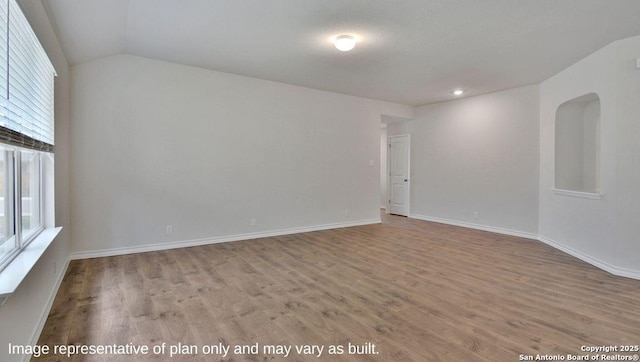 empty room with baseboards, wood finished floors, plenty of natural light, and vaulted ceiling