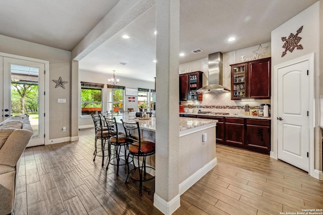 101 La Rosa Dr, Blanco, TX 78606 - kitchen featuring a kitchen breakfast bar, light stone counters, light wood finished floors, and wall chimney exhaust hood