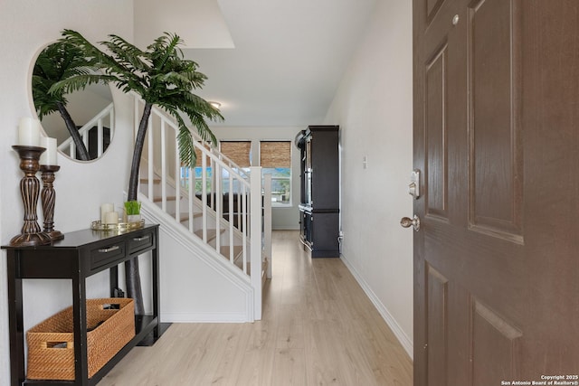 hallway with stairway, light wood-style flooring, and baseboards